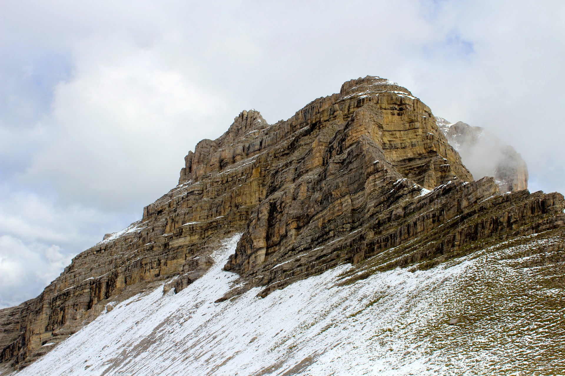 a mountain covered in snow with a cloud in the sky